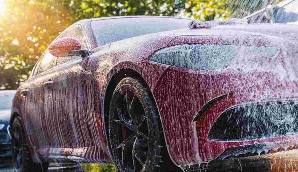 Lavaggio di un auto rossa piena di sapone