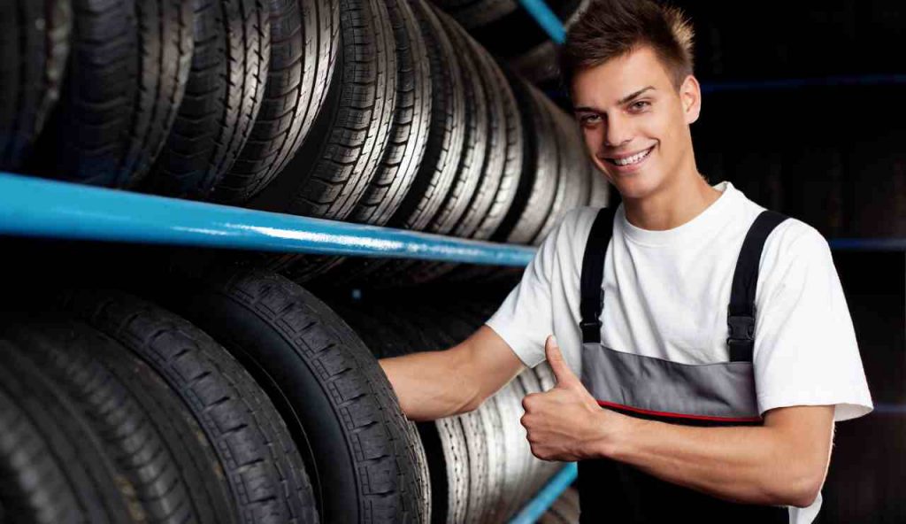 Meccanico insieme a delle gomme di auto