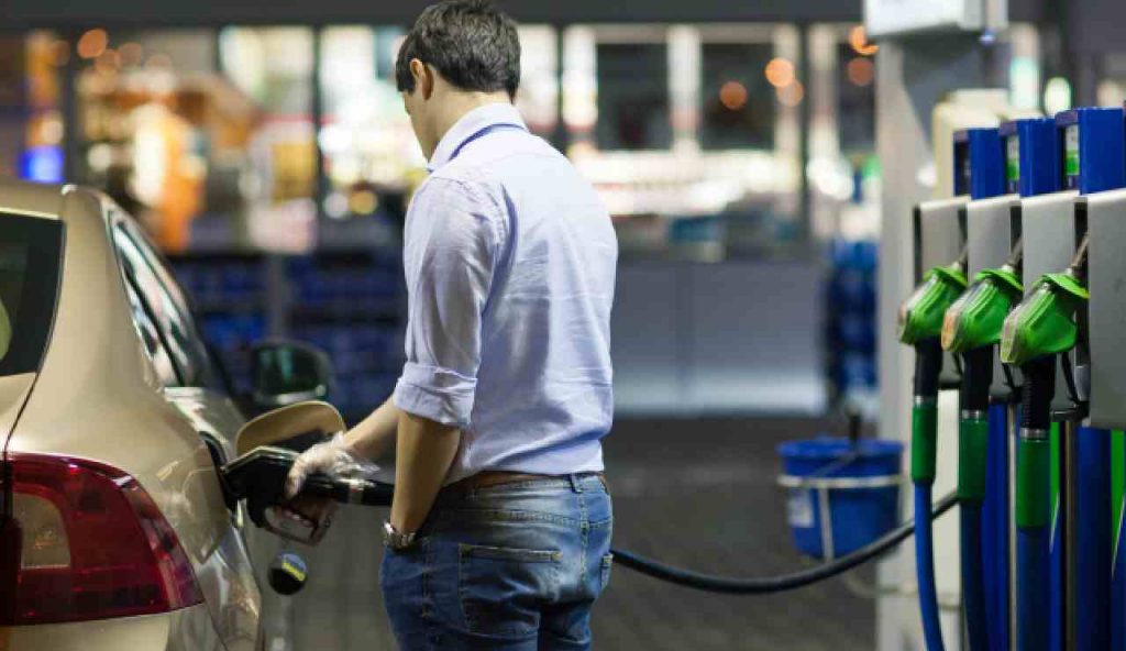 Persona effettua rifornimento alla pompa di benzina