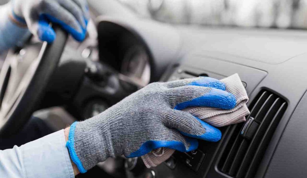 Persona pulisce il cruscotto di un'auto